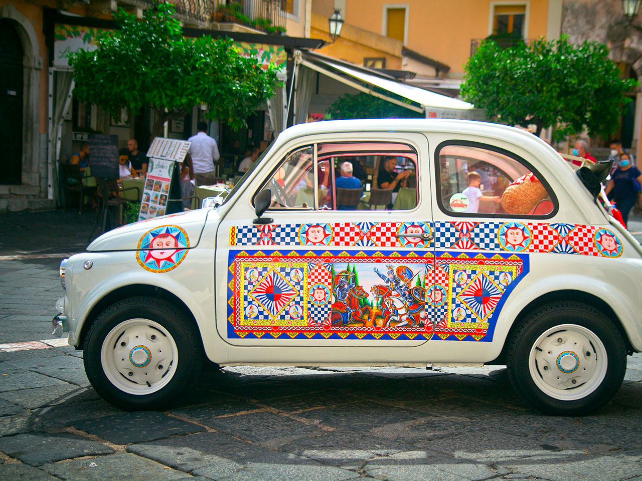 white vintage fiat 500, decorated with Sicilian graphics, in the streets of Taormina