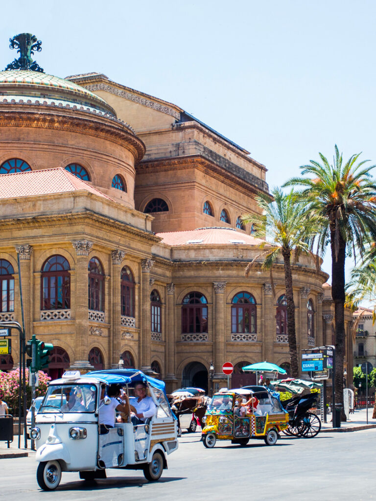 Ape motorbikes whizzing past the Teatro Massimo in Palermo