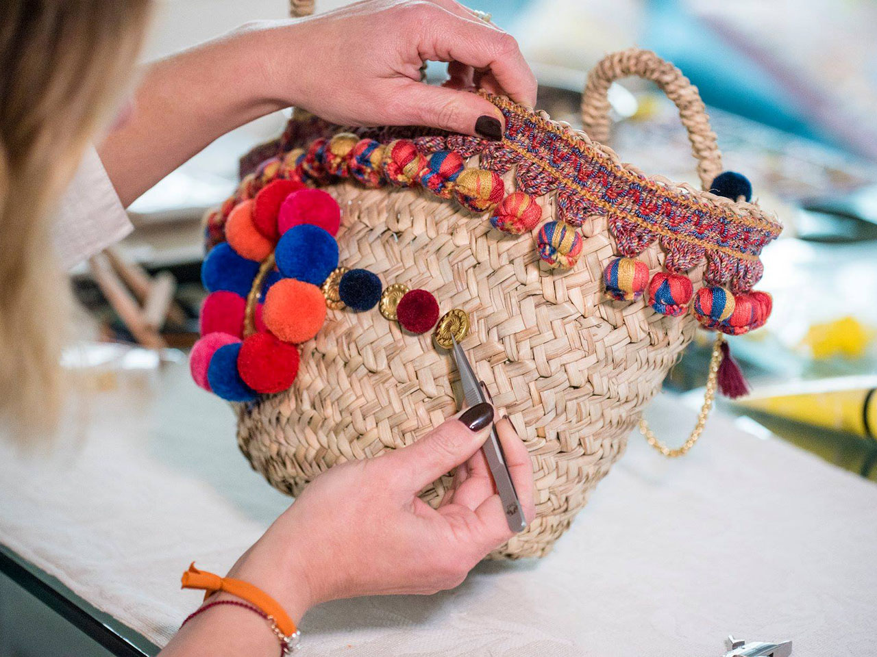 artisan decorating a "crow's nest", a woven straw bag