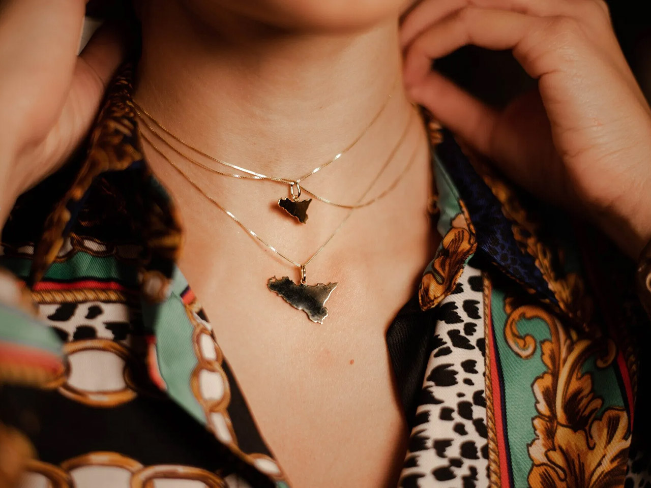 necklaces with sicily-shaped charms worn by a woman