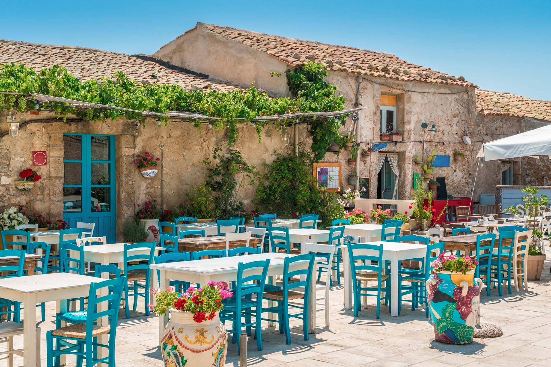Marzamemi square with the characteristic tables with blue chairs