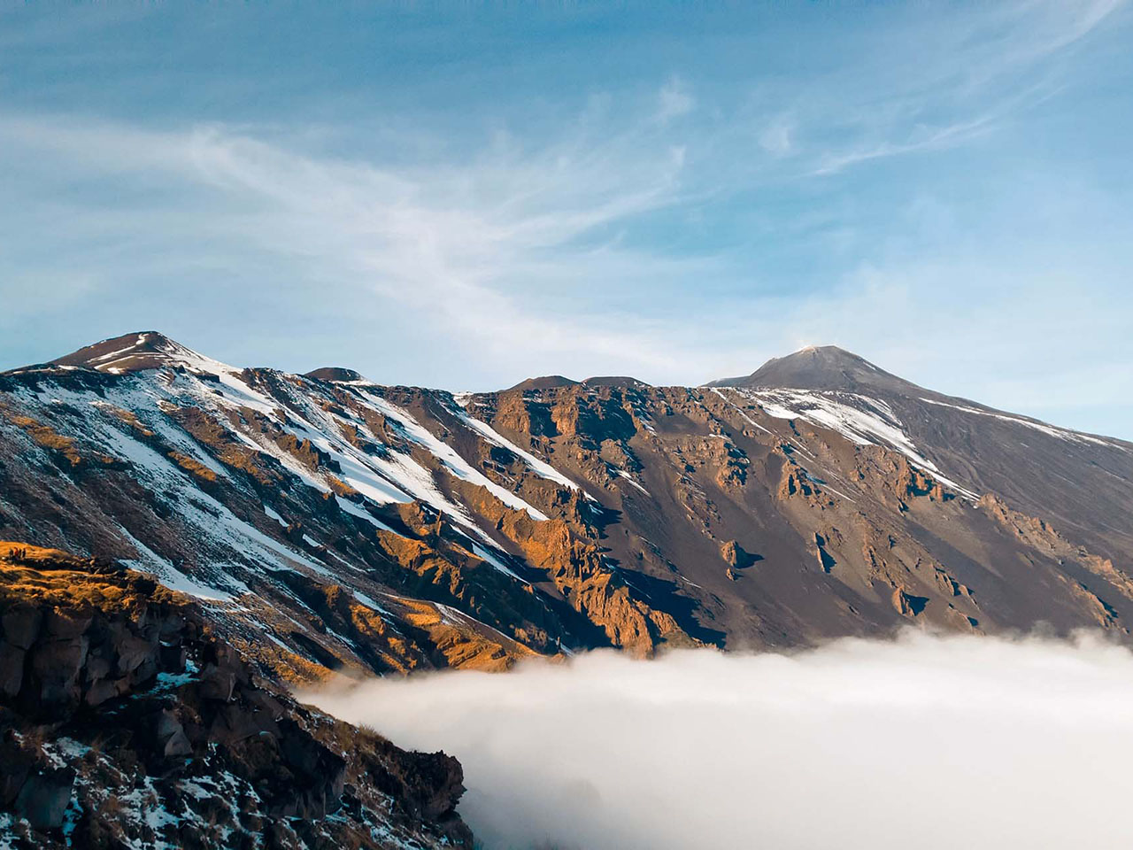 peaks of the Etna volcano, with snow and clouds