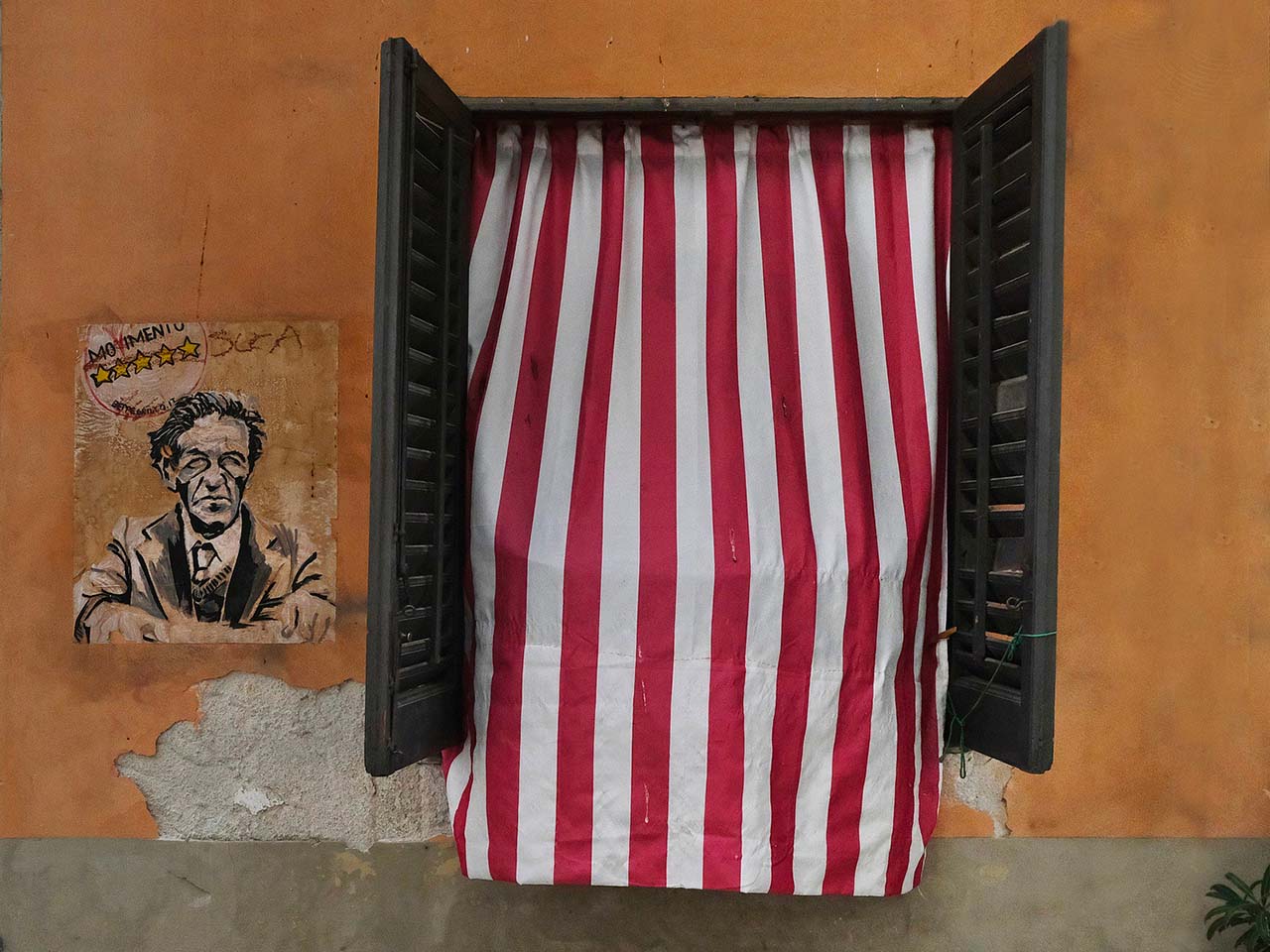 open window with red and white striped curtain with street art work next to it