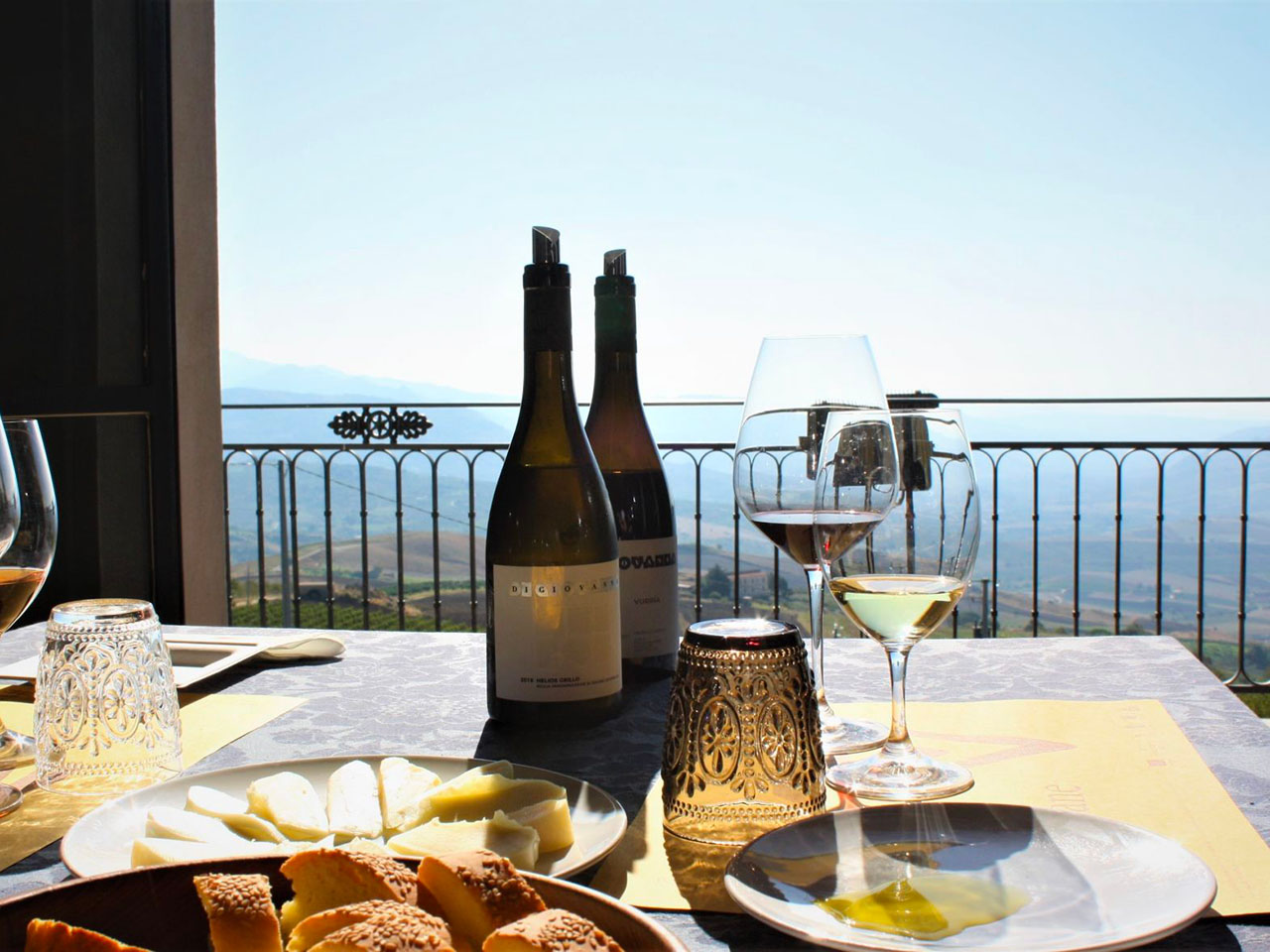 table with wine and cheeses overlooking the Sicilian hills